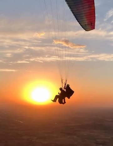 Parapente biplace devant le coucher du soleil